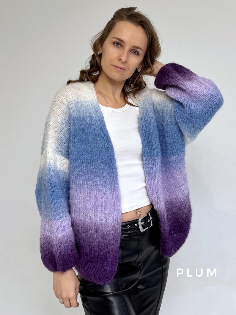 Puede incluir: Un c&aacute;rdigan de manga larga y abertura frontal con un patr&oacute;n de color degradado. El c&aacute;rdigan es blanco en la parte superior, pasando a azul claro, luego a morado y finalmente a morado oscuro en la parte inferior. El c&aacute;rdigan est&aacute; hecho de un hilo suave y esponjoso.