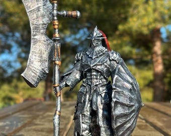 May include: A detailed figurine of a knight in full armor, holding a large battle axe and a shield. The armor is primarily silver with black accents, and the axe has a textured blade. The knight has a red plume on the helmet. The figurine is standing on a wooden surface.