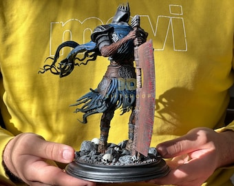 May include: A detailed figurine of a knight in dark armor, holding a large red sword. The knight has a blue cape and is standing on a base with skulls and rocks. The figurine is held in front of a yellow background. The text "BD GIFTSHOOP" is visible.