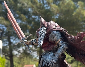 May include: A detailed figurine of a knight in silver armor, holding a large red sword. The knight has a long white beard and a red cloak. The background is blurred, with green trees and a hint of blue sky.