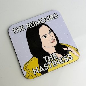 Peut inclure: Un dessous de verre violet et blanc avec une illustration de dessin anim&eacute; d'une femme aux cheveux noirs et une veste jaune. Le texte sur le dessous de verre est "The Rumours The Nastiness".
