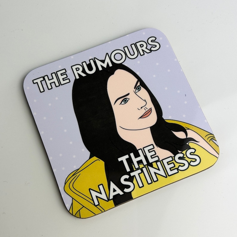 Peut inclure: Un dessous de verre violet et blanc avec une illustration de dessin anim&eacute; d'une femme aux cheveux noirs et une veste jaune. Le texte sur le dessous de verre est "The Rumours The Nastiness".