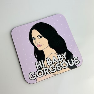 Peut inclure: Un dessous de verre violet et blanc avec une illustration de dessin anim&eacute; d'une femme aux longs cheveux noirs et le texte "Hi Baby Gorgeous".