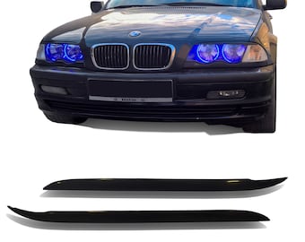 Könnte beinhalten: Ein schwarzer BMW 3er Limousine mit blauen LED-Scheinwerfern und einer schwarzen Frontstoßstange. Das Auto hat ein schwarzes Nummernschild mit dem Wort "BMW" darauf. Das Bild zeigt auch zwei schwarze Kunststoff-Zierleisten für das Auto.