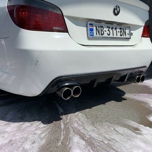 Puede incluir: Un sedán BMW Serie 5 blanco con un difusor trasero negro y dos salidas de escape. El coche tiene una matrícula que dice "NB-311-BN".