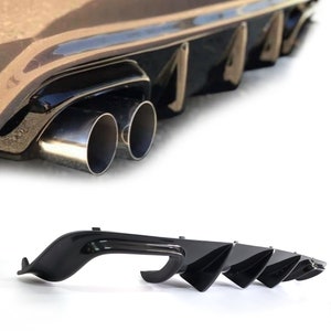 Könnte beinhalten: Schwarzer Kunststoff-Heckdiffusor mit vier Finnen für ein Auto. Der Diffusor hat eine glatte, glänzende Oberfläche und ist so konzipiert, dass er die Aerodynamik verbessert und das Erscheinungsbild des Fahrzeugs aufwertet.