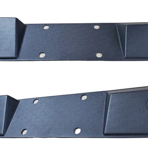 Könnte beinhalten: Zwei schwarze Kunststoffplatten mit abgerundeten Kanten und mehreren Löchern. Die Platten haben eine strukturierte Oberfläche und einen erhöhten rechteckigen Abschnitt an einem Ende.