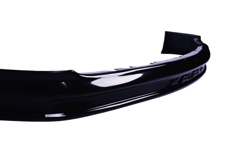 May include: Black plastic car rear bumper with a smooth, glossy finish. The bumper has a slight curve and a small lip on the bottom edge. The word "ELAN" is embossed on the right side of the bumper.