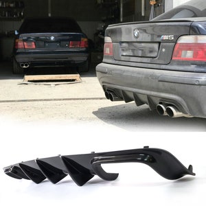 May include: Black rear diffuser for a BMW 5 Series E39. The diffuser has four fins and a center section with a lip. The diffuser is made of high-quality ABS plastic and is designed to improve the car's aerodynamics and give it a more aggressive look.