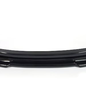 Puede incluir: Un aler&oacute;n de parachoques delantero de coche negro con un acabado liso y brillante. El aler&oacute;n tiene un dise&ntilde;o de tres piezas con una forma curva.