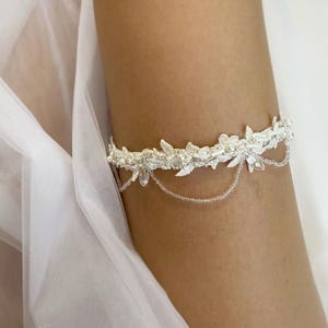 May include: White lace garter with a beaded chain and crystal embellishments.