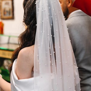 Peut inclure: Un voile de mariée blanc avec des embellissements en perles. Le voile est fait de tulle doux et est parfait pour une cérémonie de mariage.