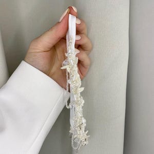 May include: White bridal garter with delicate beaded floral embellishments and a satin ribbon.