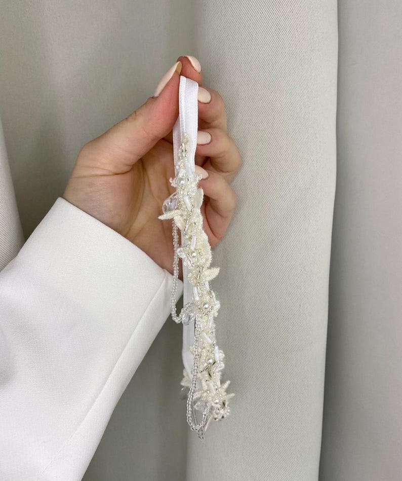 May include: White bridal garter with delicate beaded floral embellishments and a satin ribbon.
