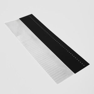 May include: Two long, rectangular strips. One is black with a dotted line down the center. The other is translucent white with evenly spaced, parallel lines. Both strips are angled across a white background.