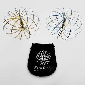 May include: Two metal flow rings, one gold and one iridescent blue, are displayed above a black drawstring bag. The bag features a white floral design and the text "Flow Rings" with the tagline "interactive, tactile, decorative, fun!"