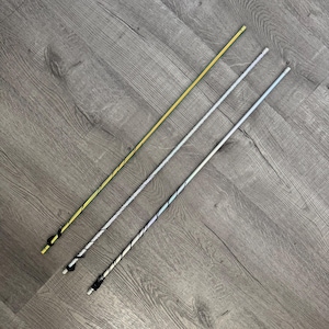 May include: Three decorative wands in gold, silver, and iridescent finishes. Each wand has a twisted design and a black accent at the handle. The wands are lying diagonally on a grey wooden surface.