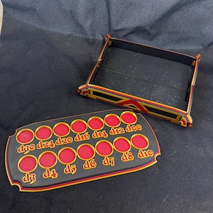 May include: A black and red dice tray and dice holder set. The dice holder has 15 red circular slots with gold trim and numbers. The tray is black with gold and red trim.