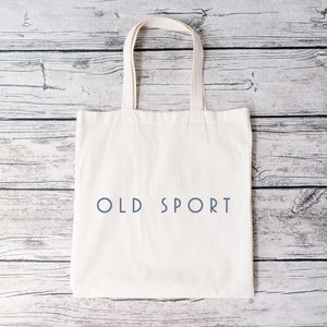 K&ouml;nnte beinhalten: Wei&szlig;e Stofftasche mit dem Aufdruck "OLD SPORT" in Blau.