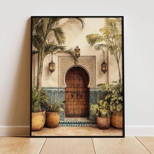 May include: A framed print of an arched wooden door with intricate carvings, flanked by palm trees and potted plants. The artwork features a warm color palette with beige walls, blue and white tiles, and hanging lanterns, evoking a sense of an exotic courtyard.