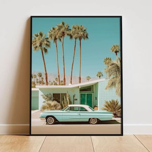 May include: Framed print featuring a vintage turquoise car parked in front of a mid-century modern house with palm trees under a clear blue sky. The artwork evokes a retro, desert aesthetic.