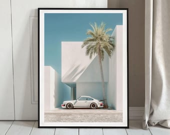 May include: A framed art print featuring a white sports car parked in front of a modern white building with a palm tree. The sky is a clear blue, and the print is in a black frame.