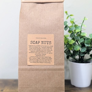 May include: A brown paper bag with a label that reads "Rooted Essentials Soap Nuts". The label explains that soap nuts are berries that form a hard shell and contain saponins, a natural soap. The label also includes instructions for using the soap nuts in a washing machine.