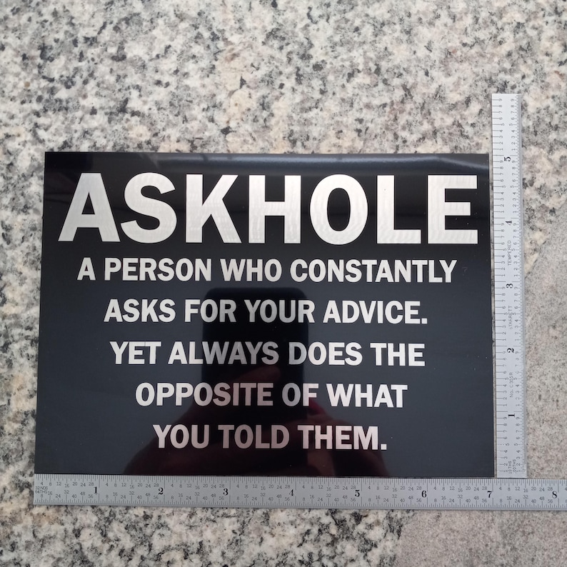 May include: Black sign with white text that reads "ASKHOLE A PERSON WHO CONSTANTLY ASKS FOR YOUR ADVICE. YET ALWAYS DOES THE OPPOSITE OF WHAT YOU TOLD THEM."