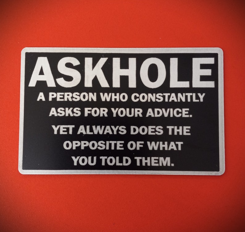 May include: A black and silver sign with the text "ASKHOLE" in white letters. The sign reads "A person who constantly asks for your advice. Yet always does the opposite of what you told them."