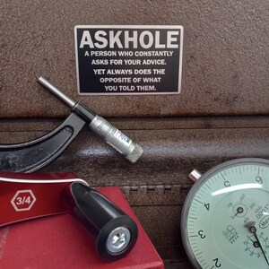 May include: A silver metal sign with black text that reads "ASKHOLE A PERSON WHO CONSTANTLY ASKS FOR YOUR ADVICE. YET ALWAYS DOES THE OPPOSITE OF WHAT YOU TOLD THEM."