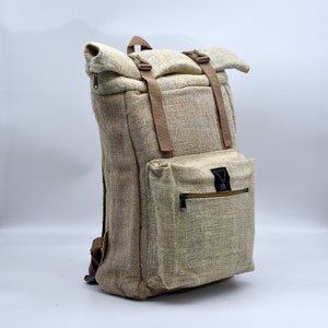 Könnte beinhalten: Ein beigefarbener Hanfrucksack mit braunen Trägern und einer Reißverschlusstasche vorne. Die Tasche hat ein schwarzes Dreieckslogo mit dem Text "Hemp" darin.