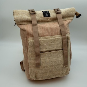 Peut inclure: Un sac à dos à fermeture par enroulement en tissu tissé texturé beige et marron clair. Il comprend deux sangles verticales en nylon beige avec des boucles en plastique, une poche frontale zippée et une petite étiquette noire avec un logo triangle blanc.