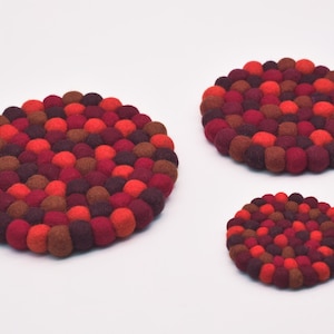 May include: Three round felt trivets in various sizes, made of red, brown, and burgundy felt balls.