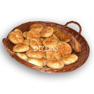 Puede incluir: Una cesta de mimbre marrón rebosante de diversos productos horneados. La cesta contiene varios panecillos dorados y una baguette crujiente. Los panecillos tienen un diseño en espiral. La imagen está bien iluminada, mostrando las texturas del pan.