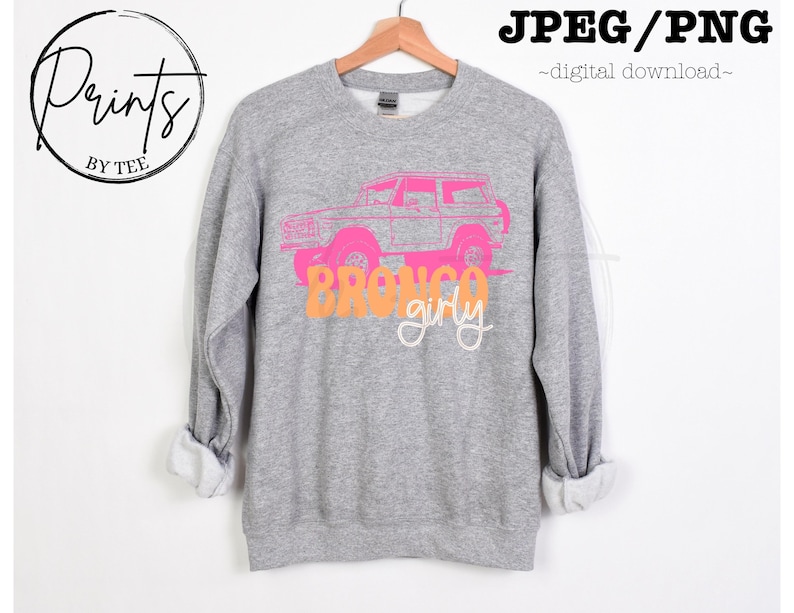 May include: Gray sweatshirt with a pink and orange graphic of a vintage Bronco truck with the text "Bronco girly".