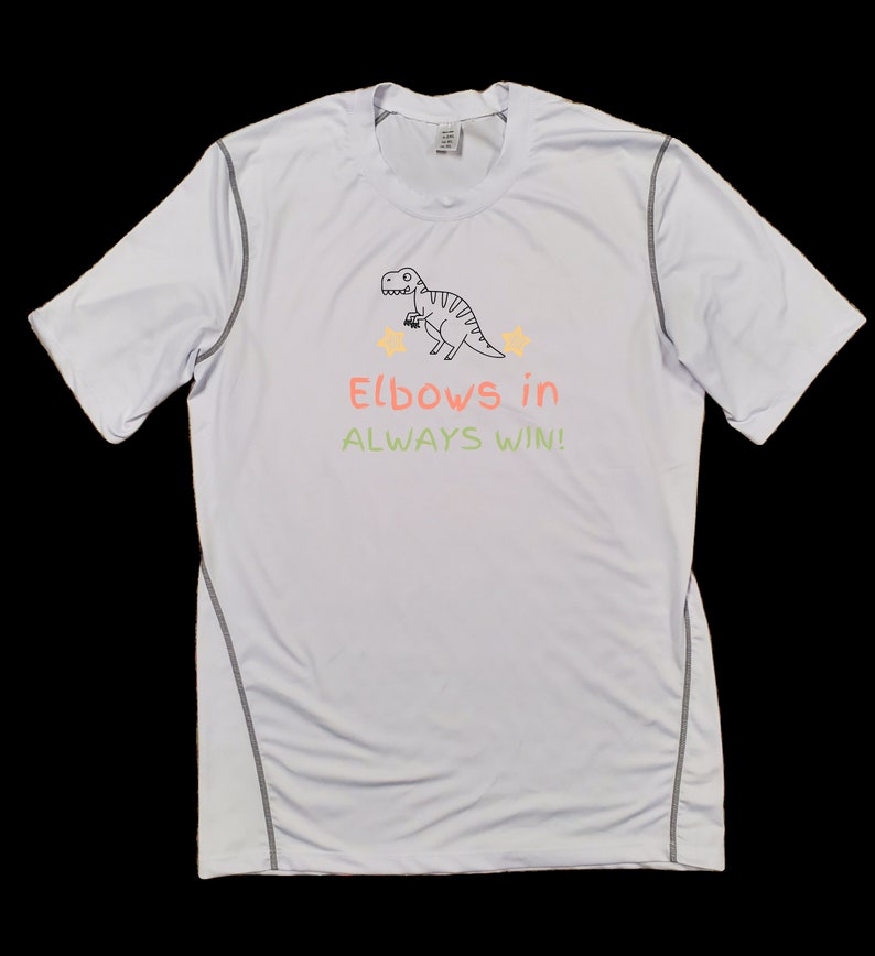 May include: White short-sleeved t-shirt with a black and white dinosaur graphic and the text "Elbows in ALWAYS WIN!" in green and orange.