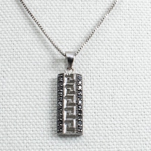 May include: A silver chain necklace with a rectangular pendant featuring a geometric design accented with black marcasite stones.