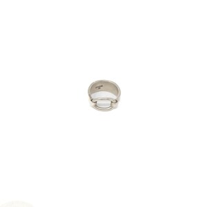 May include: A polished silver-toned metal ring featuring a smooth, continuous band with a central horizontal bar design. The interior of the band displays a small, stamped hallmark near the top edge, showcasing a clean and metallic finish throughout.