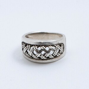 May include: A silver ring with a woven design. The ring is wide and has a textured surface.