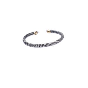 May include: A silver-toned cable-style cuff bracelet featuring a twisted metal design throughout the band. The open-ended bracelet is finished with two small, smooth, gold-toned metal caps at each terminal end, creating a distinct contrast.