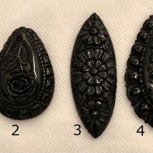 May include: Four black carved cameo pendants with floral designs. The pendants are numbered 1 through 4.