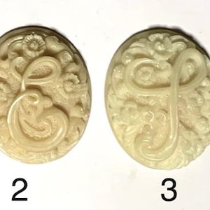 May include: Four off-white oval-shaped buttons with a raised floral design and a letter in the centre. The letters are A, E, F, and H.