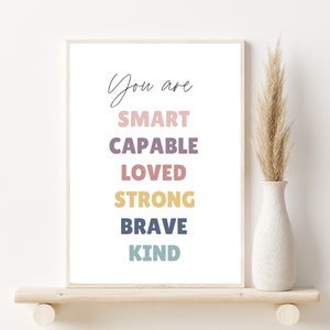 May include: A white framed print with the text "You are SMART CAPABLE LOVED STRONG BRAVE KIND" in colorful letters.