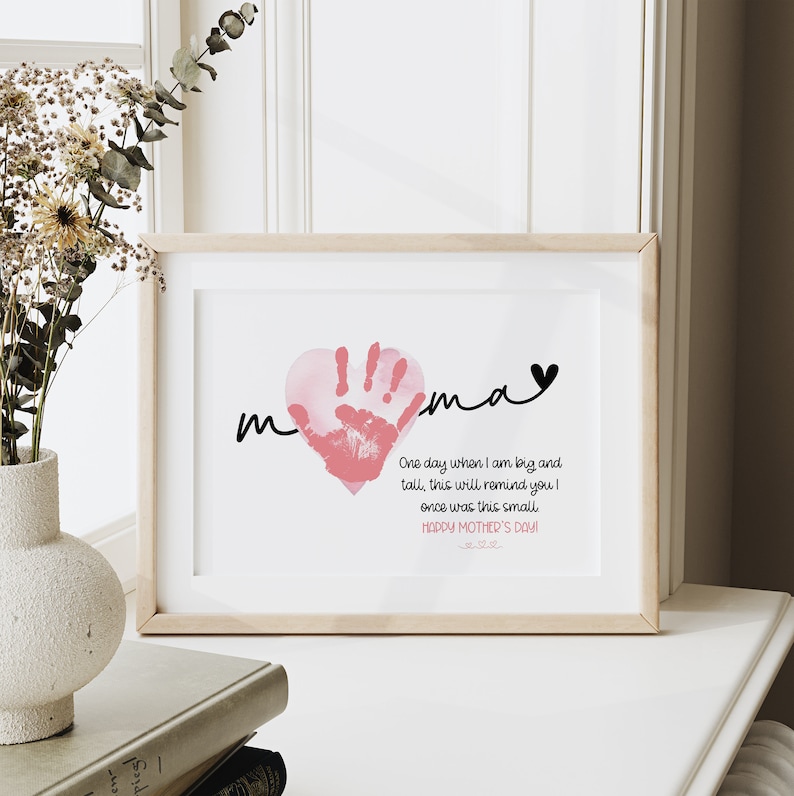 Peut inclure: Une empreinte de main rose en forme de c&oelig;ur avec le mot "mama" &eacute;crit en cursive noire au-dessus. Le texte ci-dessous indique "Un jour, quand je serai grand et grand, cela vous rappellera que j'&eacute;tais autrefois si petit. Joyeuse f&ecirc;te des m&egrave;res !"