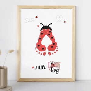 Puede incluir: Una impresi&oacute;n enmarcada con una mariquita roja hecha con huellas de manos. La mariquita tiene manchas negras y una cabeza negra con antenas. El texto "Little Love Bug" est&aacute; escrito debajo de la mariquita.