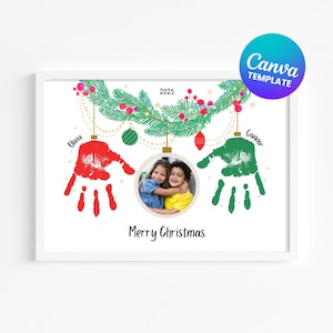 May include: A framed Christmas-themed print with a white border. The design includes a photo of two children, handprints, and the text "Merry Christmas" and "2025". The print also features a Canva template logo.
