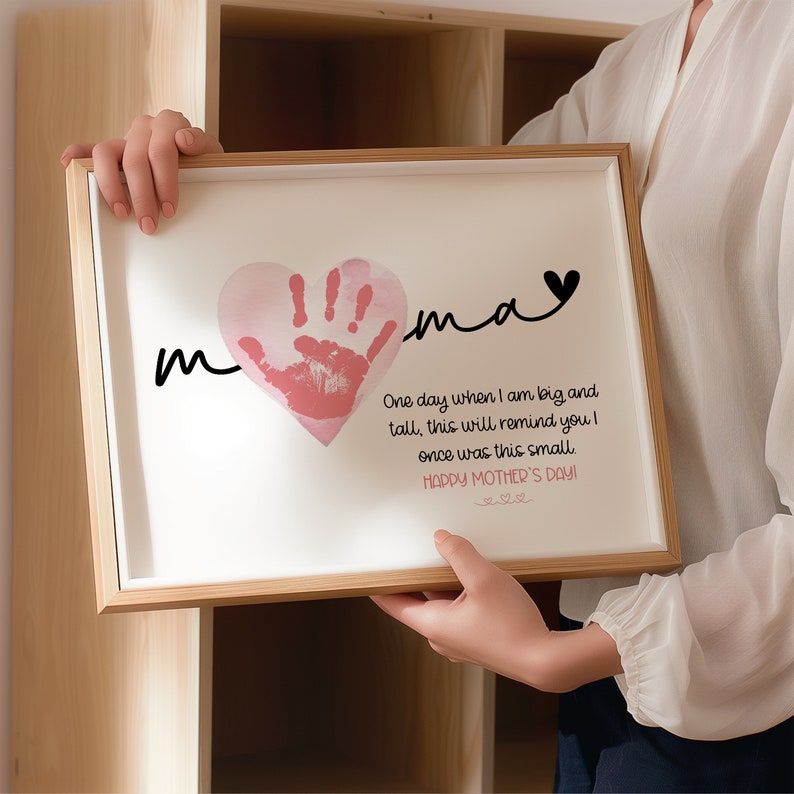 Peut inclure: Une impression encadr&eacute;e avec une empreinte de main rose en forme de c&oelig;ur. L'impression dit "mama" et "Un jour, quand je serai grand et grand, cela te rappellera que j'&eacute;tais autrefois si petit. Joyeuse f&ecirc;te des m&egrave;res !"