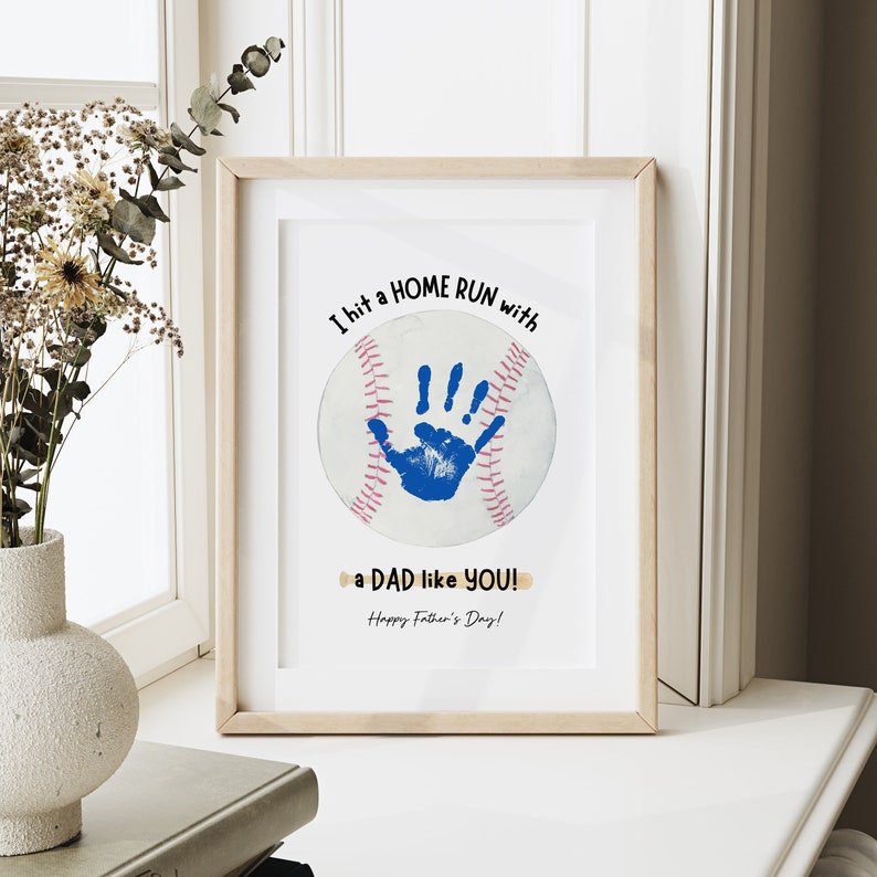 May include: A framed print with a baseball design. A blue handprint is inside the baseball. The text reads "I hit a HOME RUN with a DAD like YOU! Happy Father's Day!"