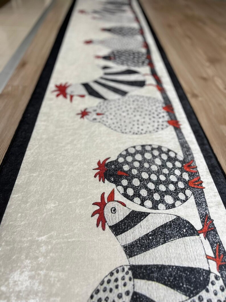 May include: A white runner rug with a black border features a line of black and white chickens with red combs. The chickens are stylized and have a whimsical design.