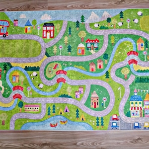Puede incluir: Una colorida alfombra de juego con un camino sinuoso, casas y un autobús. La alfombra de juego está diseñada para que los niños jueguen con coches de juguete y otros juguetes.
